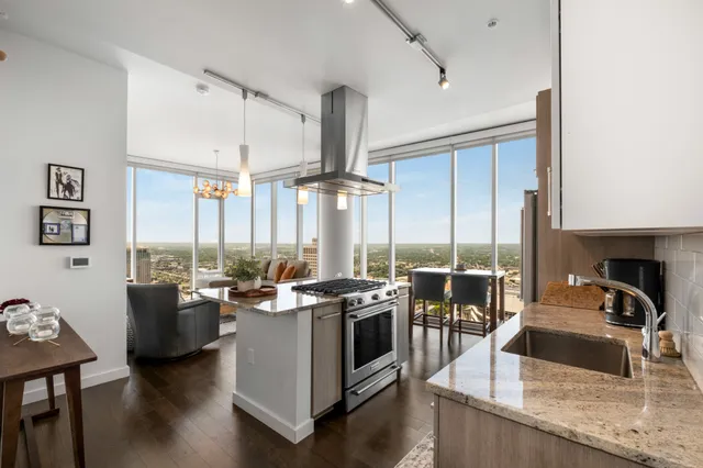 a view of a kitchen with kitchen island granite countertop a large window and stainless steel appliances