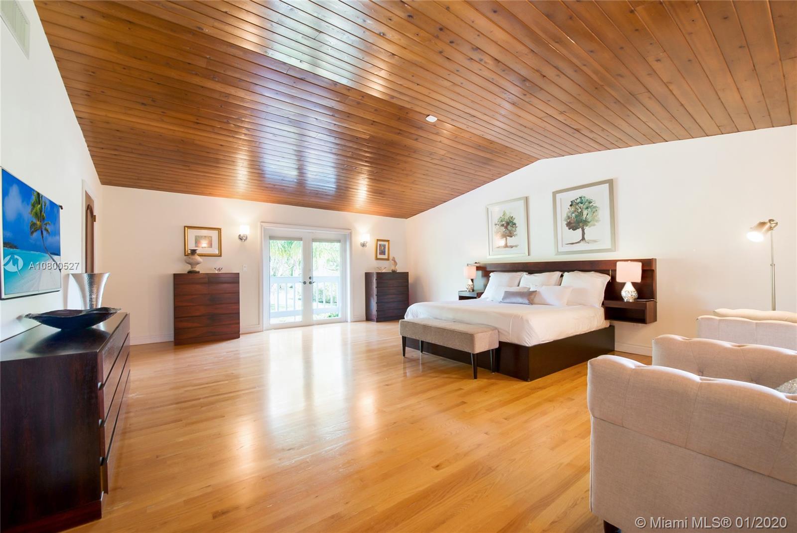 12440 Moss Ranch Road Pinecrest, FL 33156 - Photo 18 of 33 a spacious bedroom with a bed and wooden floor