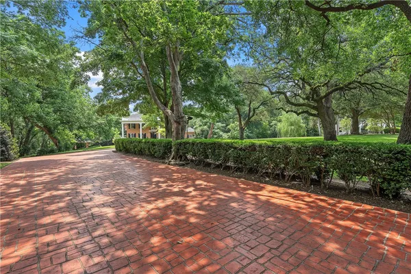 a view of house with a big yard and large trees