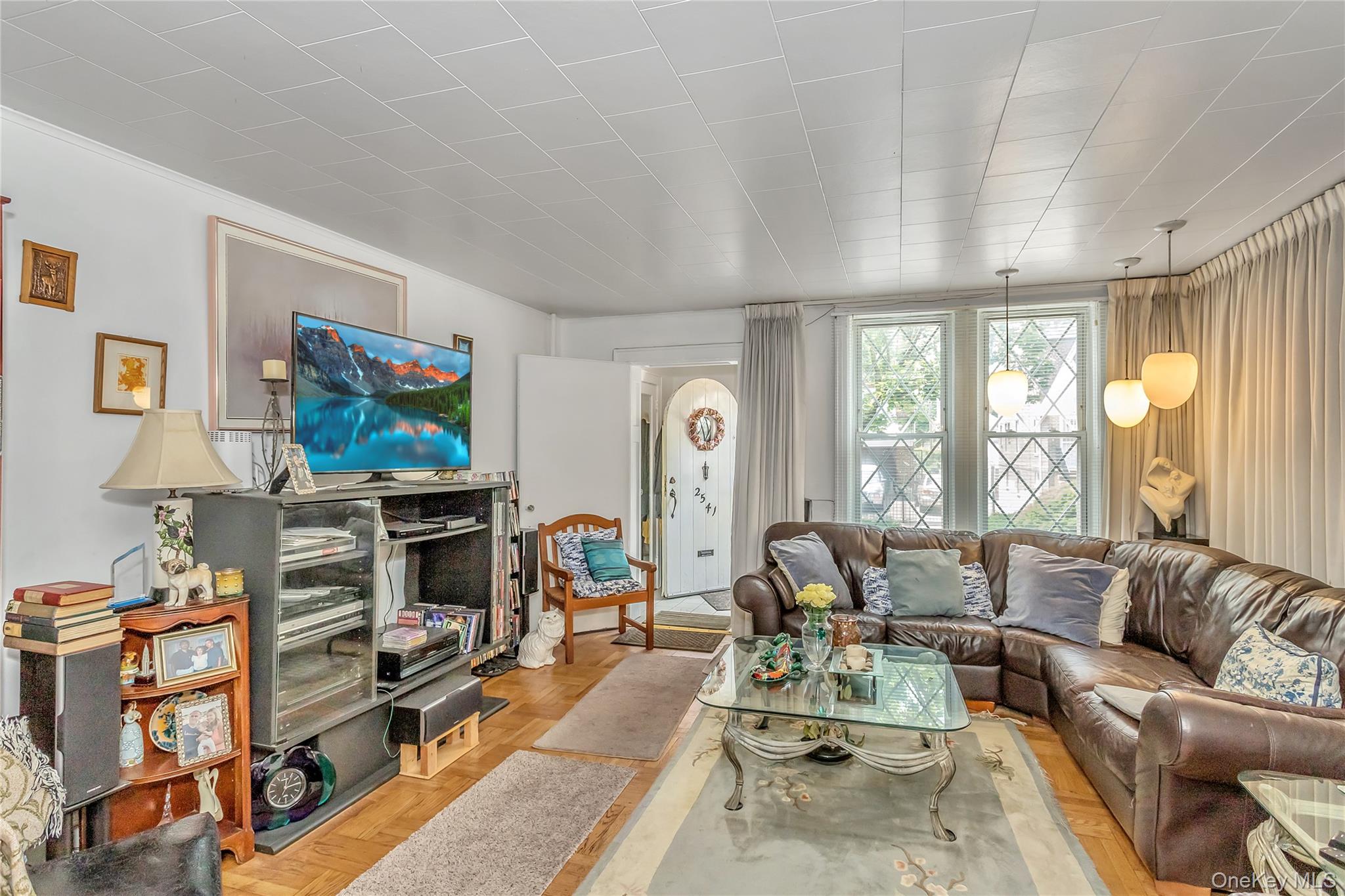 25-41 83rd Street Queens, NY 11370 - Photo 3 of 15 a living room with furniture a flat screen tv and a floor to ceiling window