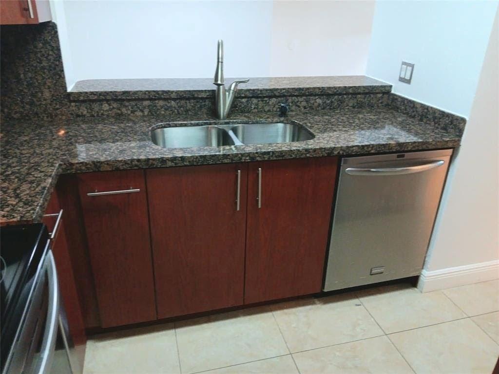1265 Southwest 46th Avenue, Unit 2207 Pompano Beach, FL 33069 - Photo 5 of 33 a kitchen with granite countertop a sink and a cabinets