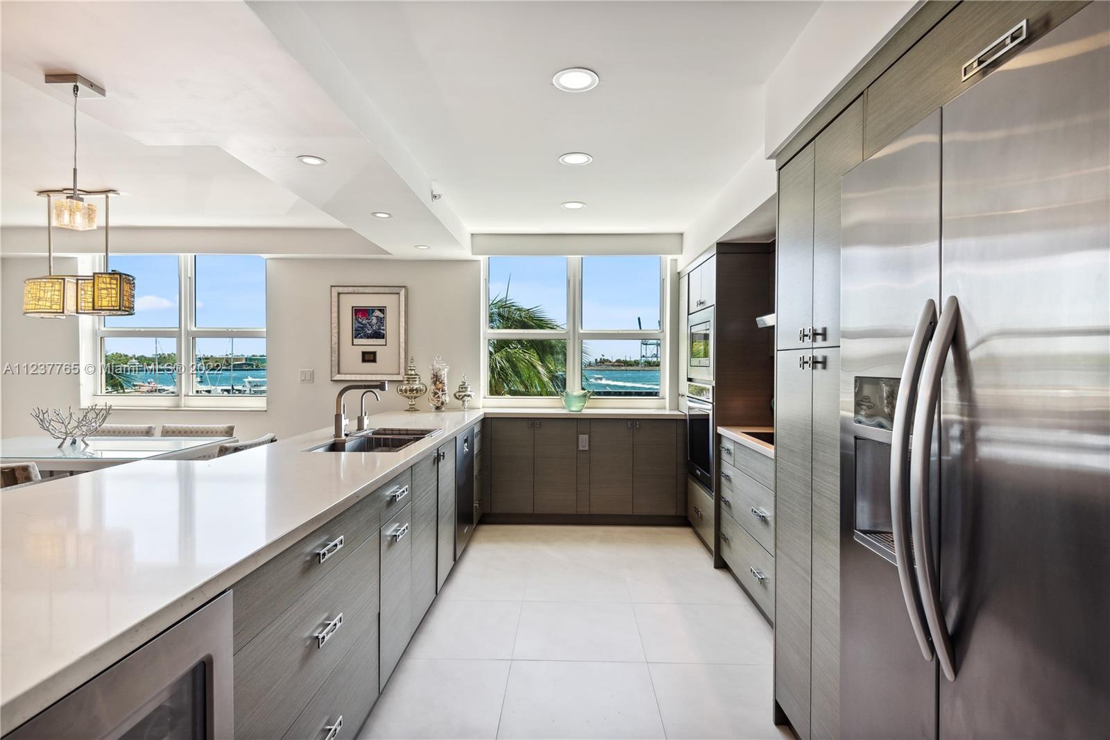 90 Alton Road, Unit TH8 Miami Beach, FL 33139 - Photo 4 of 25 a large kitchen with a large window and stainless steel appliances