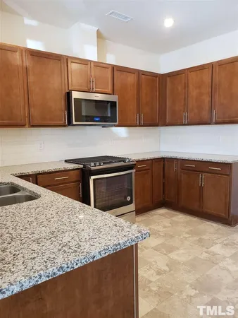 a kitchen with stainless steel appliances granite countertop a stove a sink and a microwave