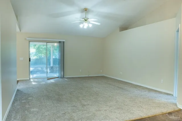 an empty room with a chandelier fan and windows