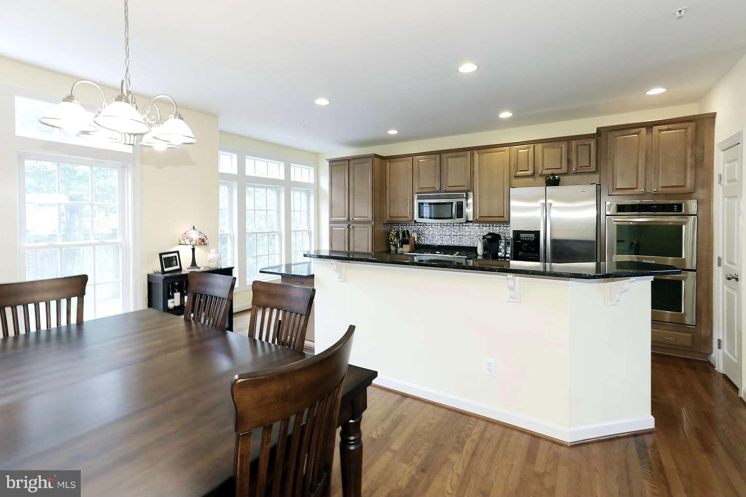 908 West Glebe Road Alexandria, VA 22305 - Photo 11 of 29 a kitchen with stainless steel appliances granite countertop a refrigerator a stove top oven a sink dishwasher a dining table and chairs with wooden floor