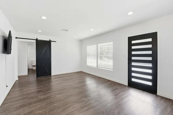 a view of an empty room with wooden floor and a window