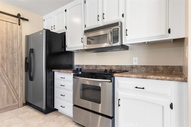 a kitchen with stainless steel appliances white cabinets white stove a microwave and a refrigerator