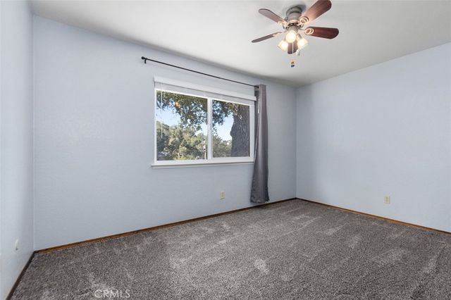 an empty room with chandelier fan and windows