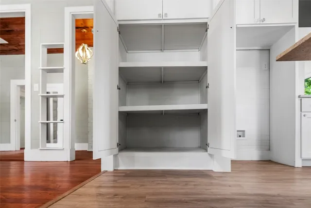 an empty room with wooden floor and cabinet