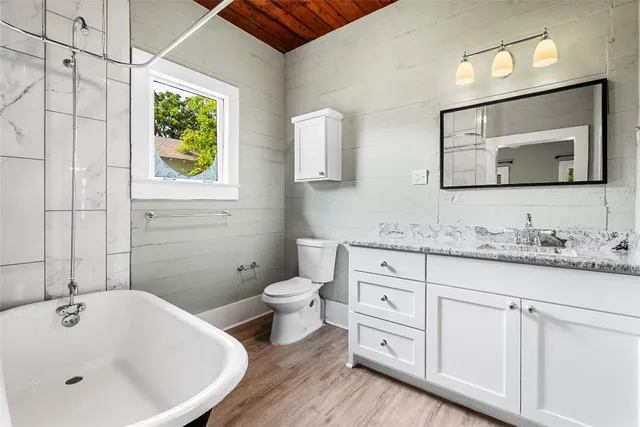 a bathroom with a granite countertop sink toilet and painting on the wall