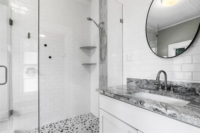 a bathroom with a granite countertop sink a mirror and a shower