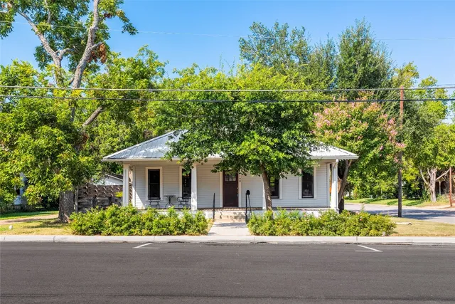 a front view of a house with a yard and potted plants