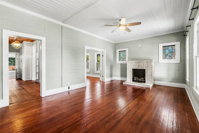 an empty room with wooden floor fireplace and windows