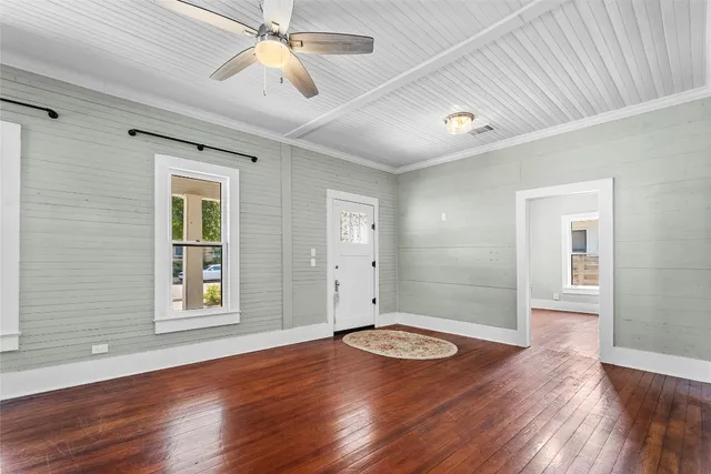 a view of empty room with wooden floor and fan