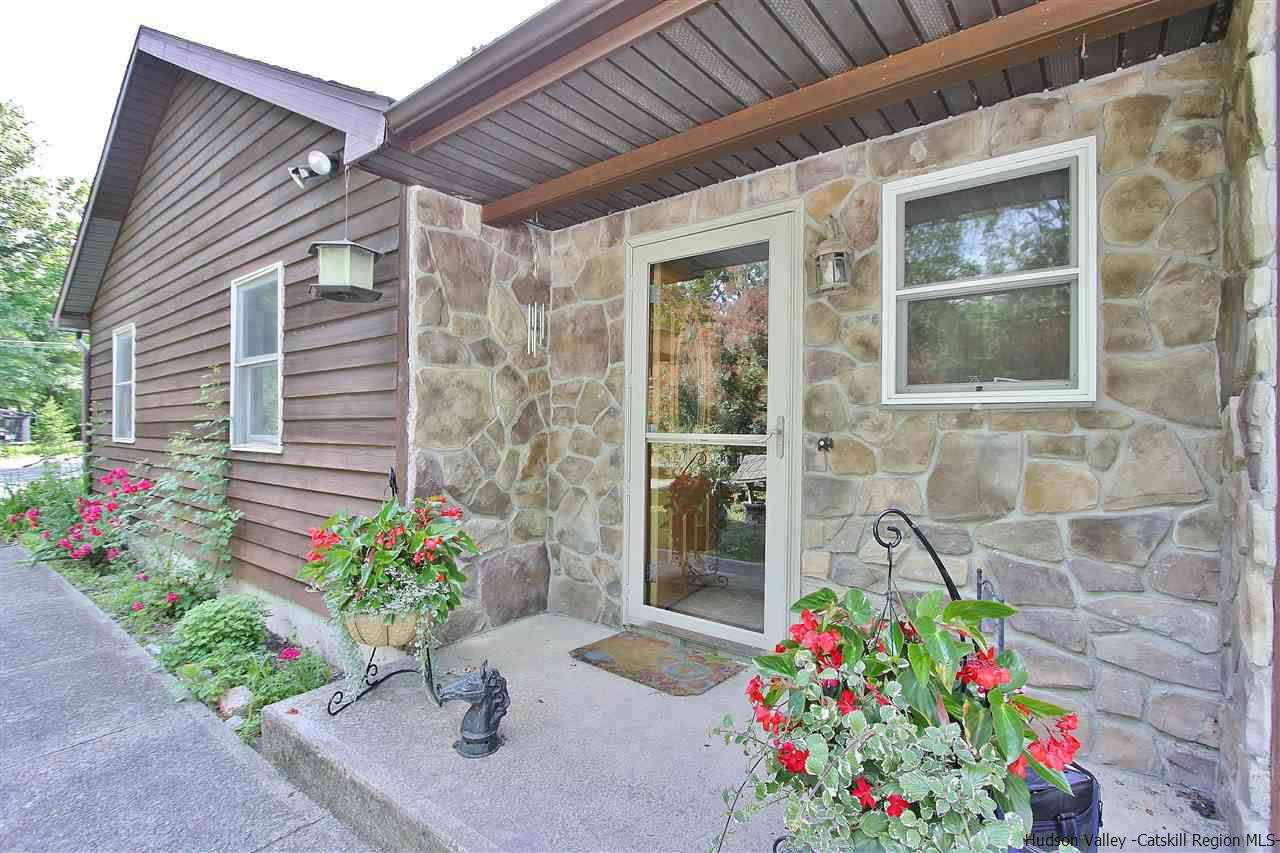 150 Nelson Hoff Road Saugerties, NY 12477 - Photo 3 of 31 a flower garden and a wooden bench in front of house