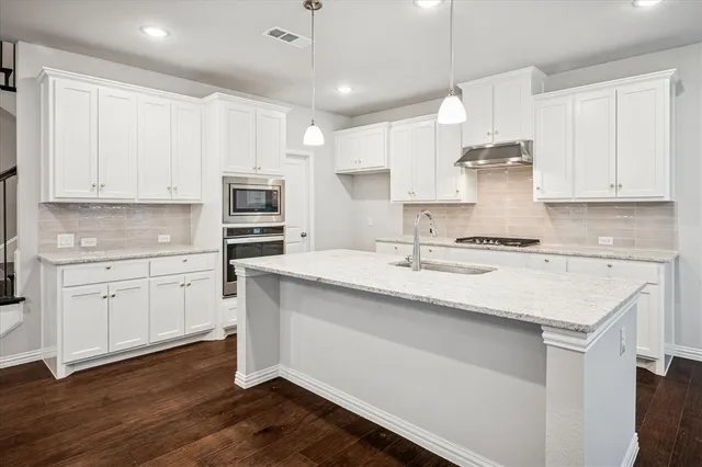 a kitchen with granite countertop a sink stove and cabinets