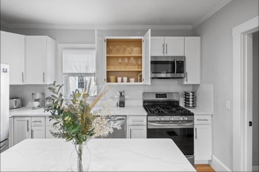 14 Everett Street, Unit 2 Medford, MA 02155 - Photo 8 of 24 a kitchen with stainless steel appliances a stove a sink a microwave and cabinets