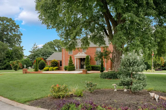 a front view of a house with a yard and trees