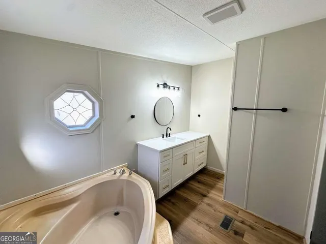 a bathroom with a tub sink and mirror