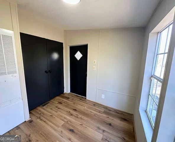 a view of an empty room with wooden floor and a window