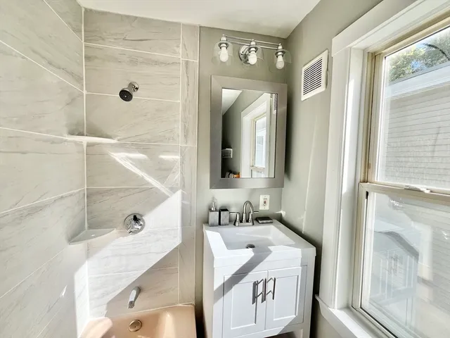a bathroom with a tub sink and mirror
