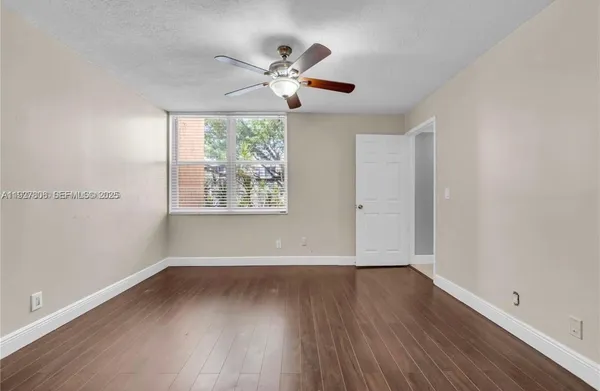 an empty room with wooden floor chandelier fan and windows
