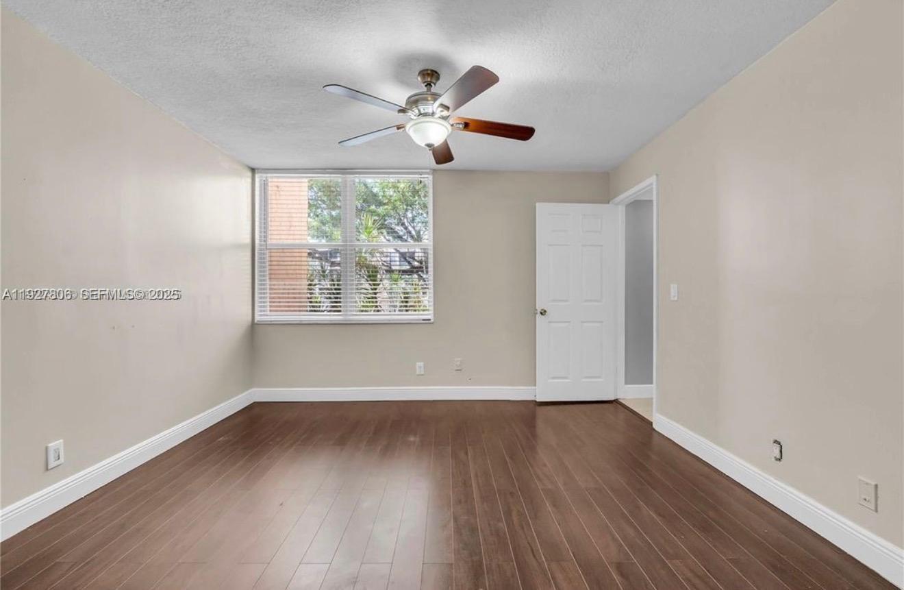 9431 Live Oak Place, Unit 205 Davie, FL 33324 - Photo 3 of 13 an empty room with wooden floor chandelier fan and windows
