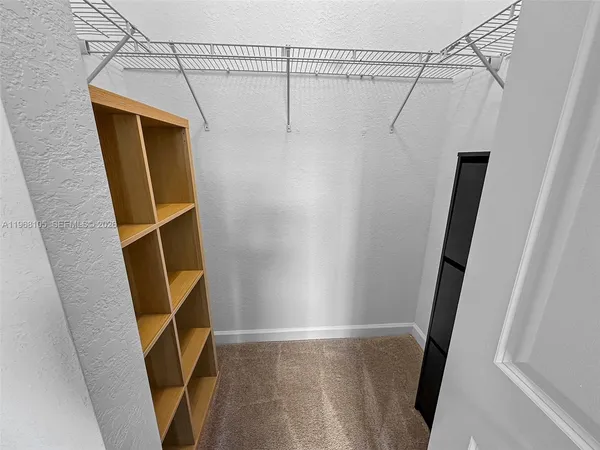 a view of walk in closet with empty space and wooden floor