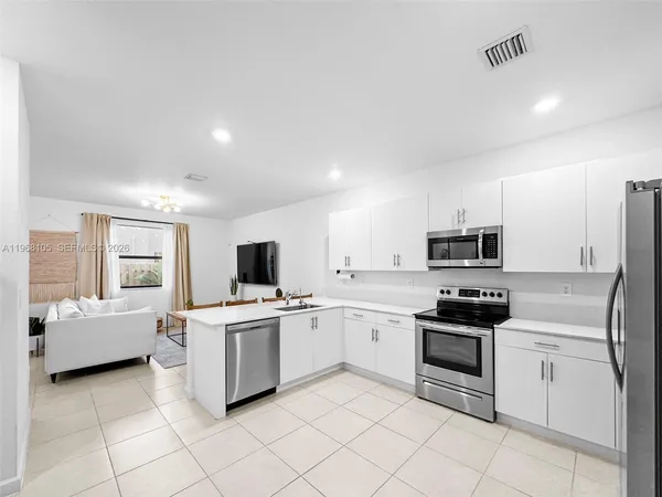 a kitchen with white cabinets and appliances
