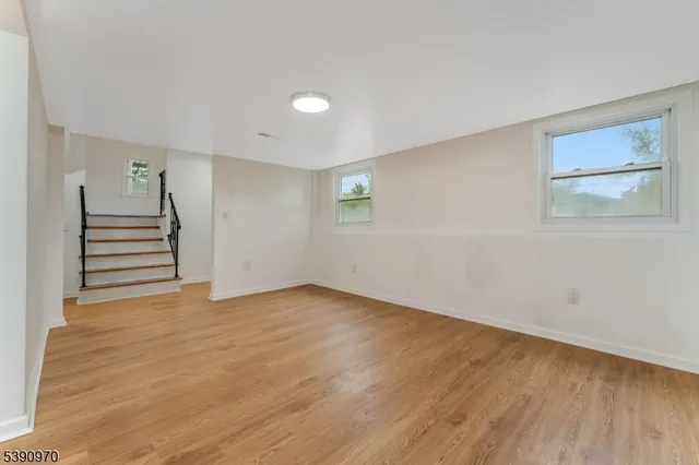 a view of an empty room with wooden floor and windows