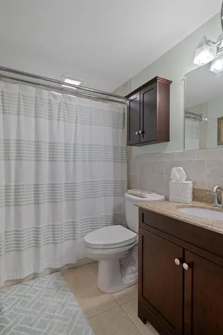 a bathroom with a granite countertop sink a toilet a mirror and shower
