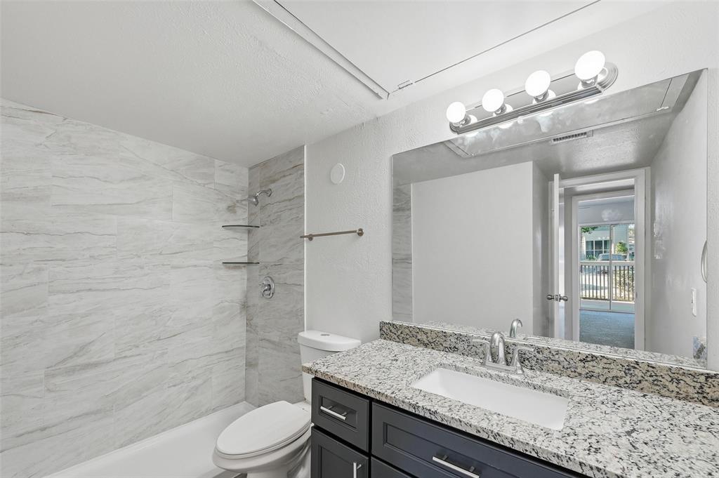 4851 Cedar Springs Road, Unit 189 Dallas, TX 75219 - Photo 13 of 29 a bathroom with a granite countertop sink toilet a mirror a vanity and shower