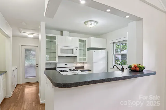 a kitchen with granite countertop a sink cabinets and wooden floor