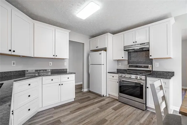 a kitchen with granite countertop white cabinets and stainless steel appliances