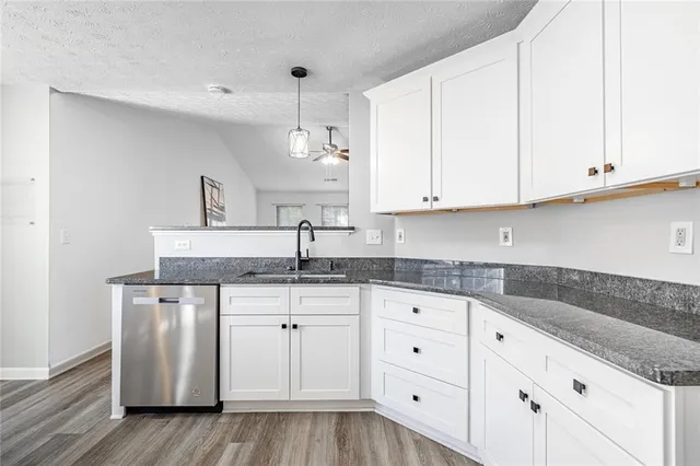 a kitchen with granite countertop a white sink and cabinets