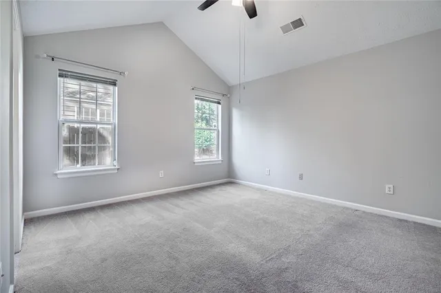 an empty room with windows and chandelier fan