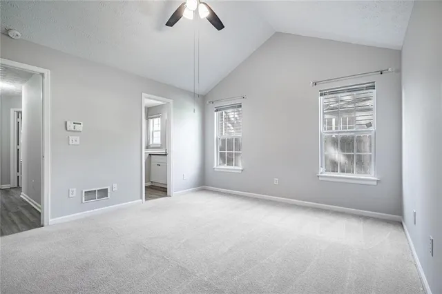 an empty room with chandelier fan and windows