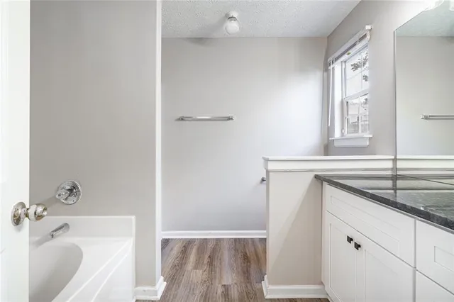 a bathroom with a granite countertop sink and a bathtub