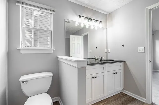 a bathroom with a granite countertop toilet a sink and a mirror