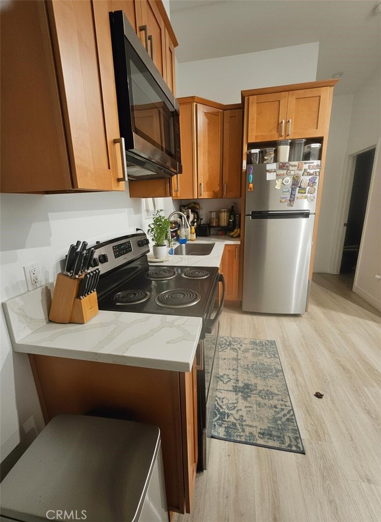 6836 Colmar Avenue, Unit 1/4 Bell Gardens, CA 90201 - Photo 2 of 6 a kitchen with a sink a stove and a refrigerator