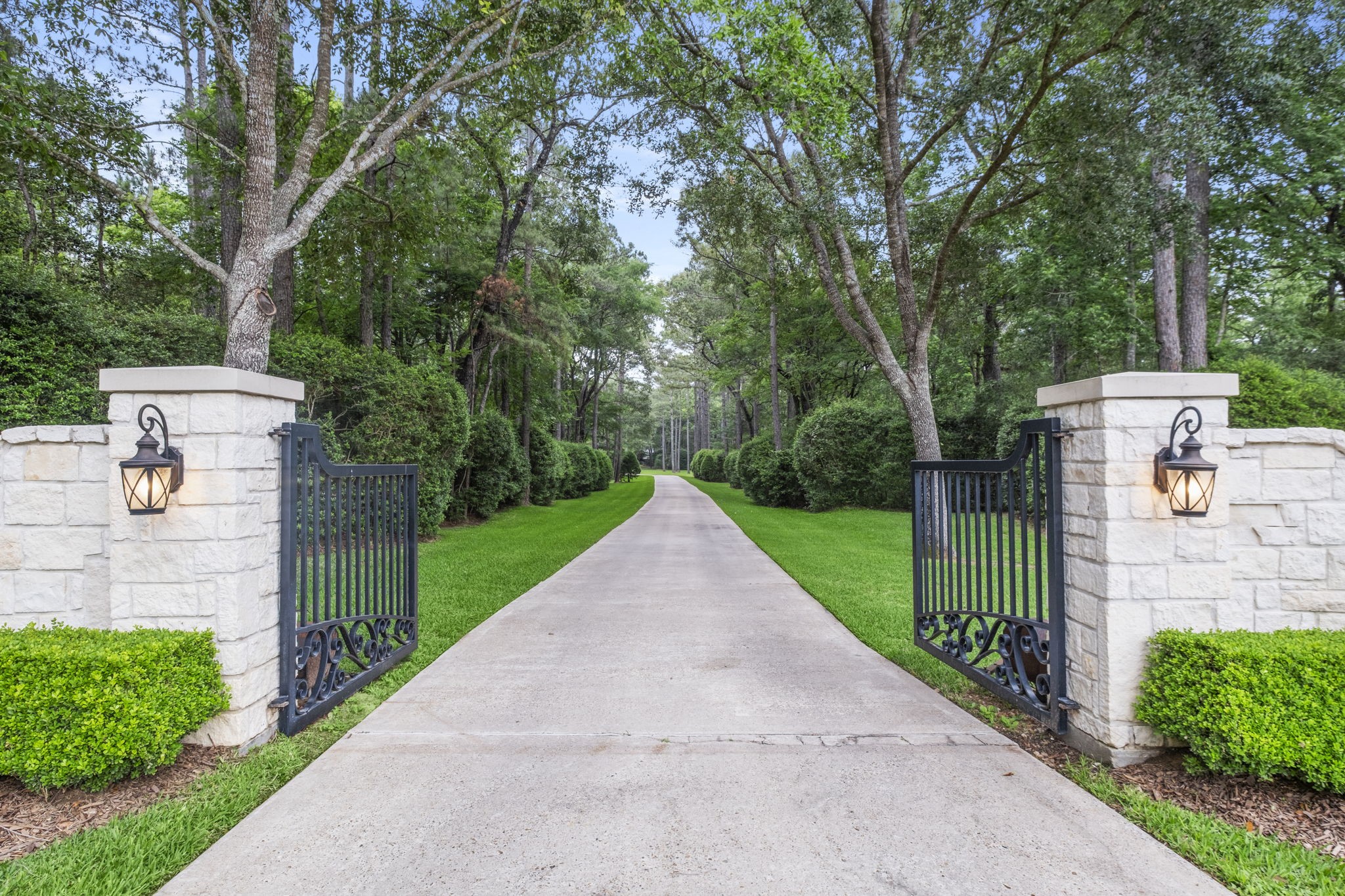 Welcome to 20010 Timber Ridge Dr! Flanked by elegant stone pillars and black wrought iron gates, the long tree-lined driveway creates the feeling of your own luxurious resort. The lush greenery and manicured hedges add a serene and private atmosphere.
