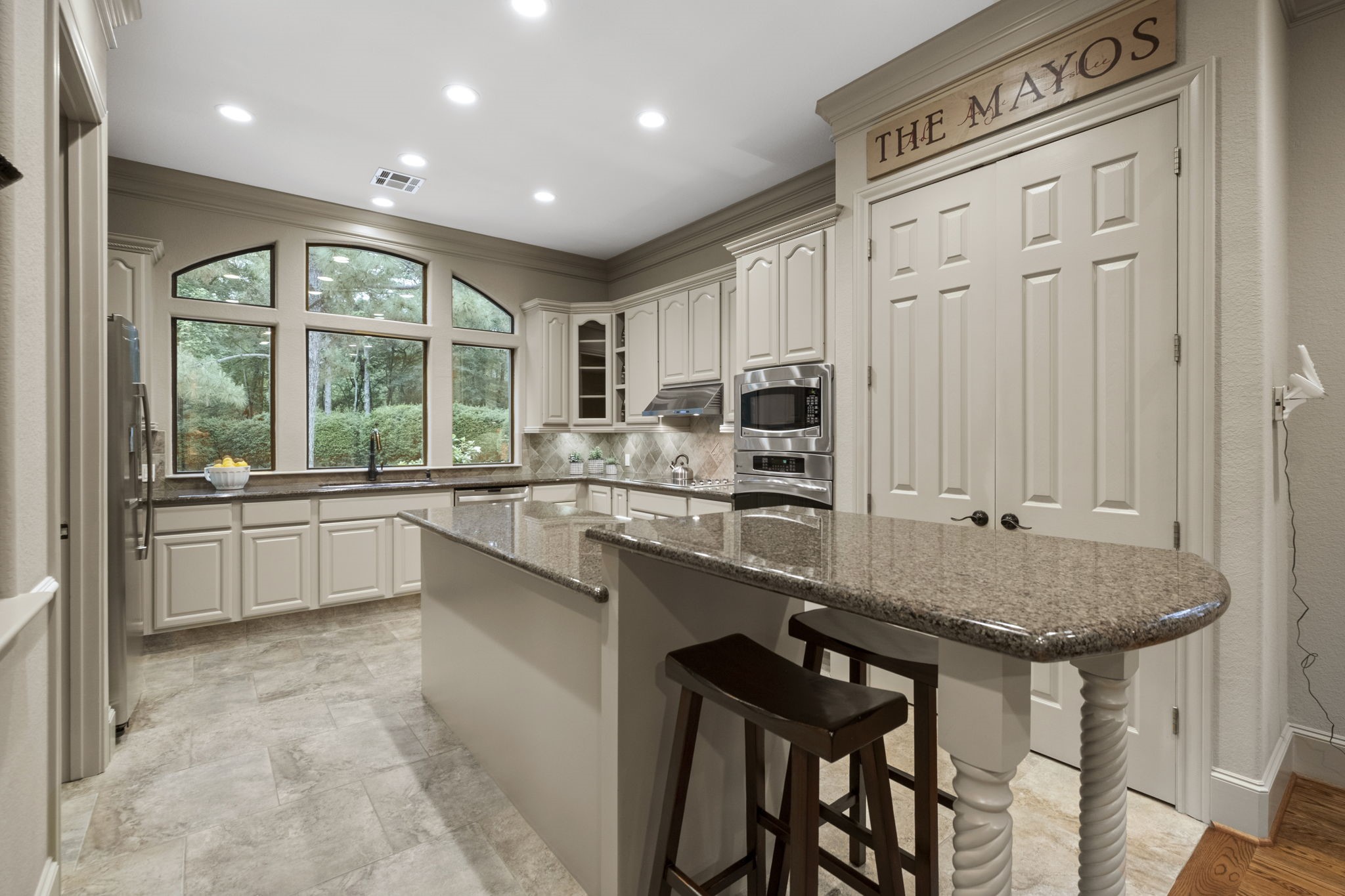 20010 Timber Ridge Drive Magnolia, TX 77355 - Photo 14 of 50 This kitchen features elegant cabinetry, granite countertops, and stainless steel appliances. The long island provides extra seating and workspace, and expansive windows offer a view of lush greenery. The space is bright and welcoming, ideal for cooking and entertaining.