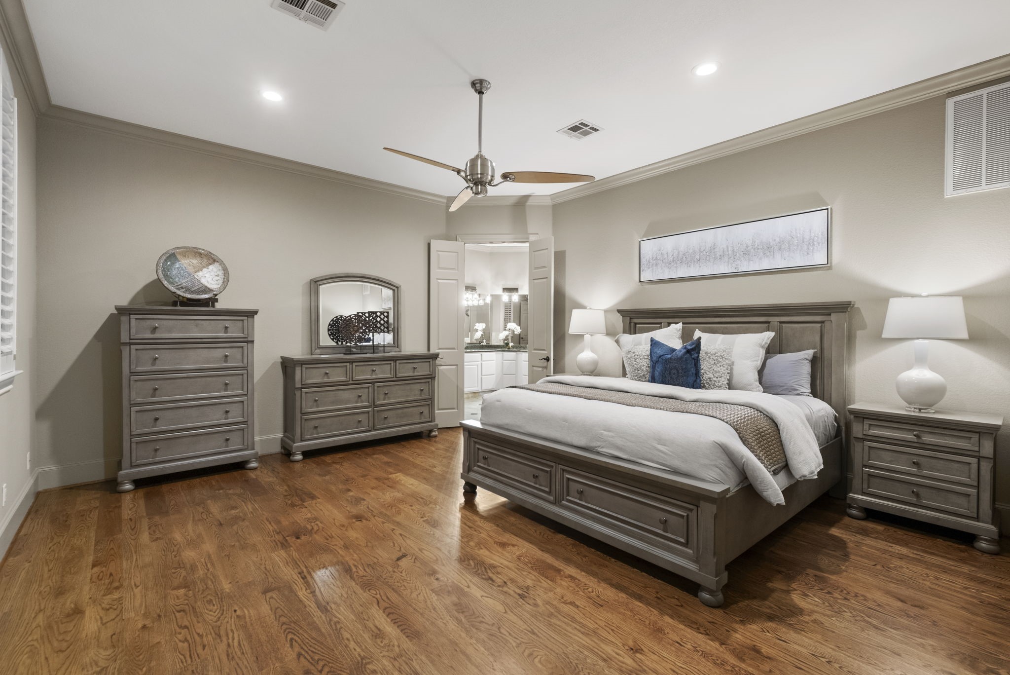 20010 Timber Ridge Drive Magnolia, TX 77355 - Photo 19 of 50 Feel swept away in this primary suite featuring hardwood floors, calming neutral walls, modern ceiling fan, and elegant lighting. Double doors lead to the private en-suite bath, enhancing the room's luxury feel.