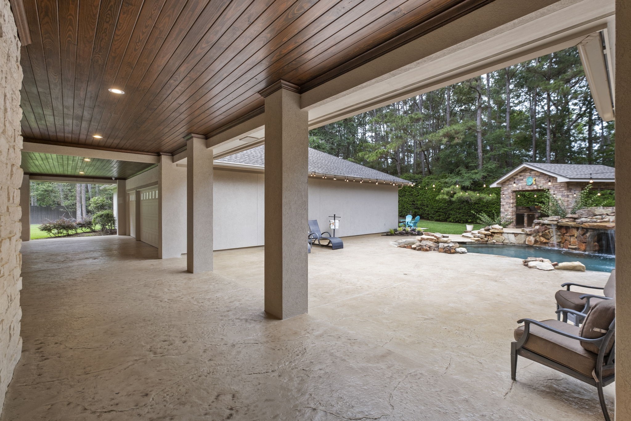 20010 Timber Ridge Drive Magnolia, TX 77355 - Photo 32 of 50 Experience seamless indoor-outdoor living with an expansive covered patio offering shaded views of the inviting pool. With ample space for seating and dining furniture and overhead lighting, this covered patio space is perfect for entertaining family and friends.
