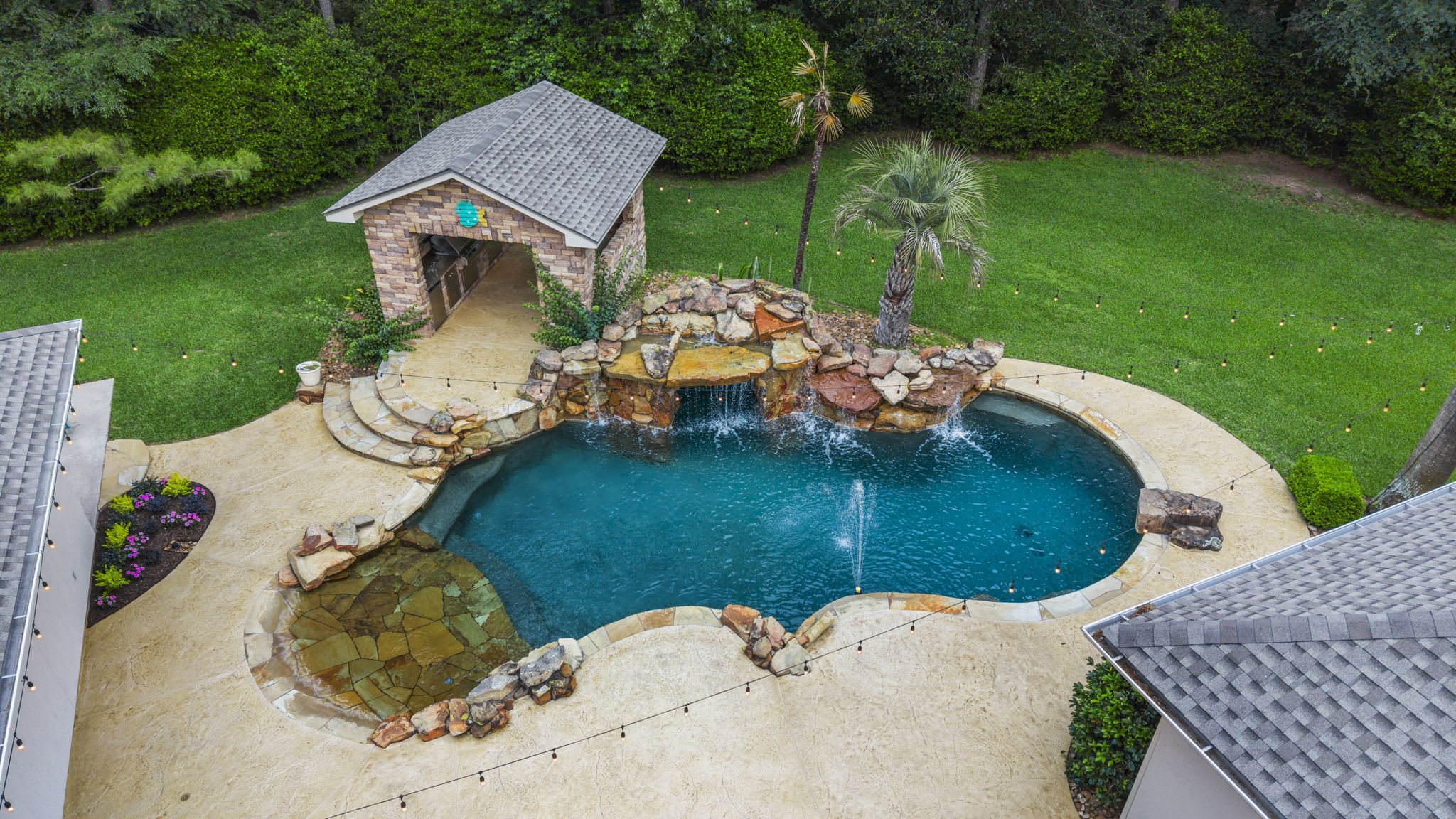 20010 Timber Ridge Drive Magnolia, TX 77355 - Photo 36 of 50 This picturesque aerial backyard view showcases the luxurious salt-water pool, patio surround, stunning outdoor kitchen, and grassy yard lined with mature trees - a haven for relaxation and entertaining.