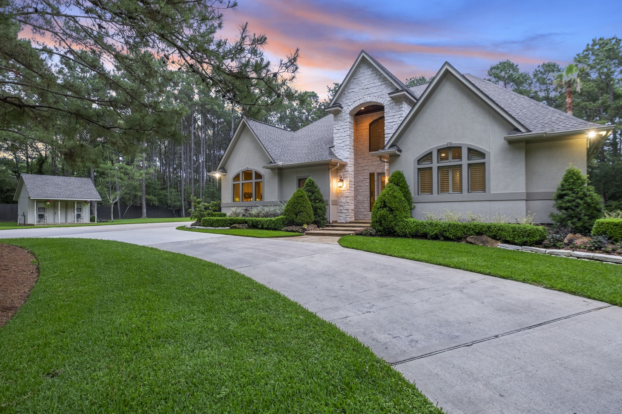 20010 Timber Ridge Drive Magnolia, TX 77355 - Photo 5 of 50 This beautiful stucco home features a modern stone facade with large arched windows and a well-maintained lawn. A spacious driveway is surrounded by lush greenery and tall trees, and a storage shed is conveniently located nearby. The roof was just recently replaced in 2025.