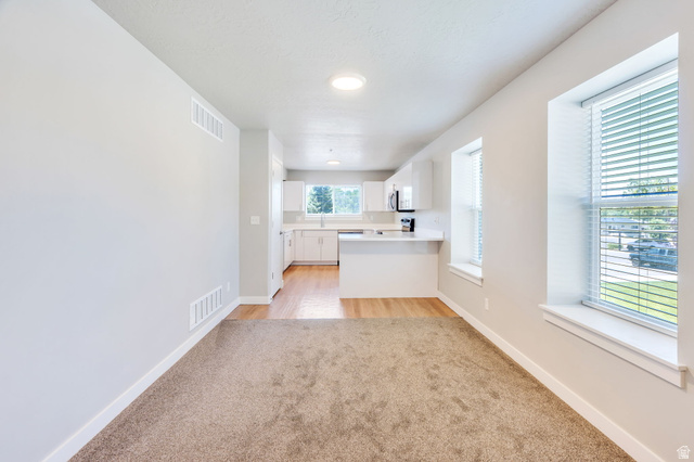 572 South 100 West, Unit E210 Springville, UT 84663 - Photo 12 of 35 Open concept living space featuring neutral paint, recessed lighting, and an integrated kitchen with white cabinetry and a breakfast bar