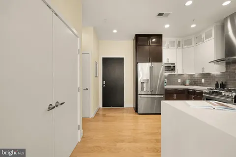a kitchen with a refrigerator a stove top oven and white cabinets