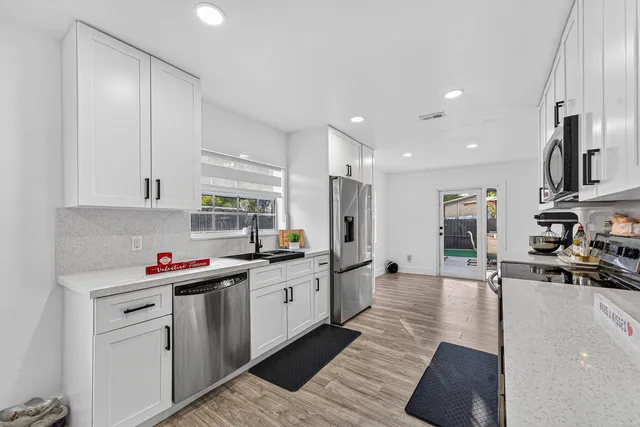 a kitchen with stainless steel appliances a sink dishwasher stove refrigerator and cabinets