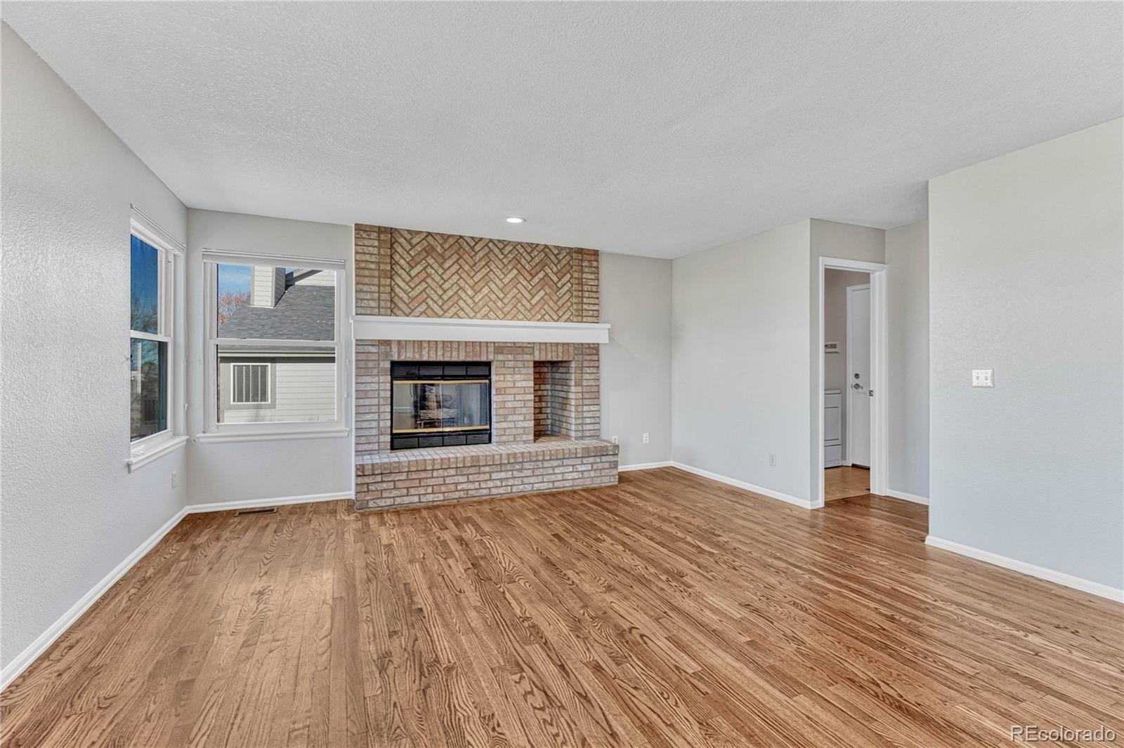 9858 Venneford Ranch Road Highlands Ranch, CO 80126 - Photo 17 of 50 a view of empty room with wooden floor and fireplace